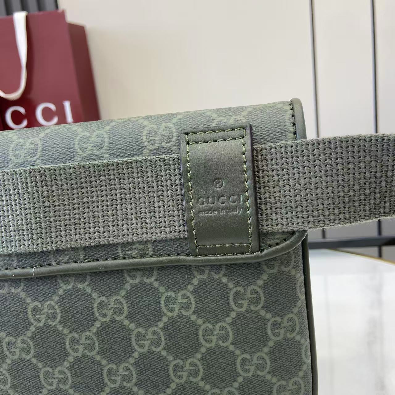 Gucci web strap attachment with leather logo patch, green and gray hardware.