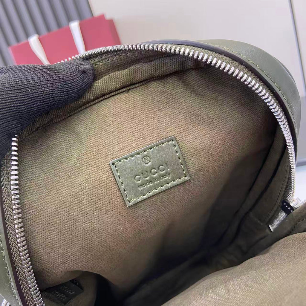 Gucci bag interior close-up showing beige lining and leather logo patch near zip