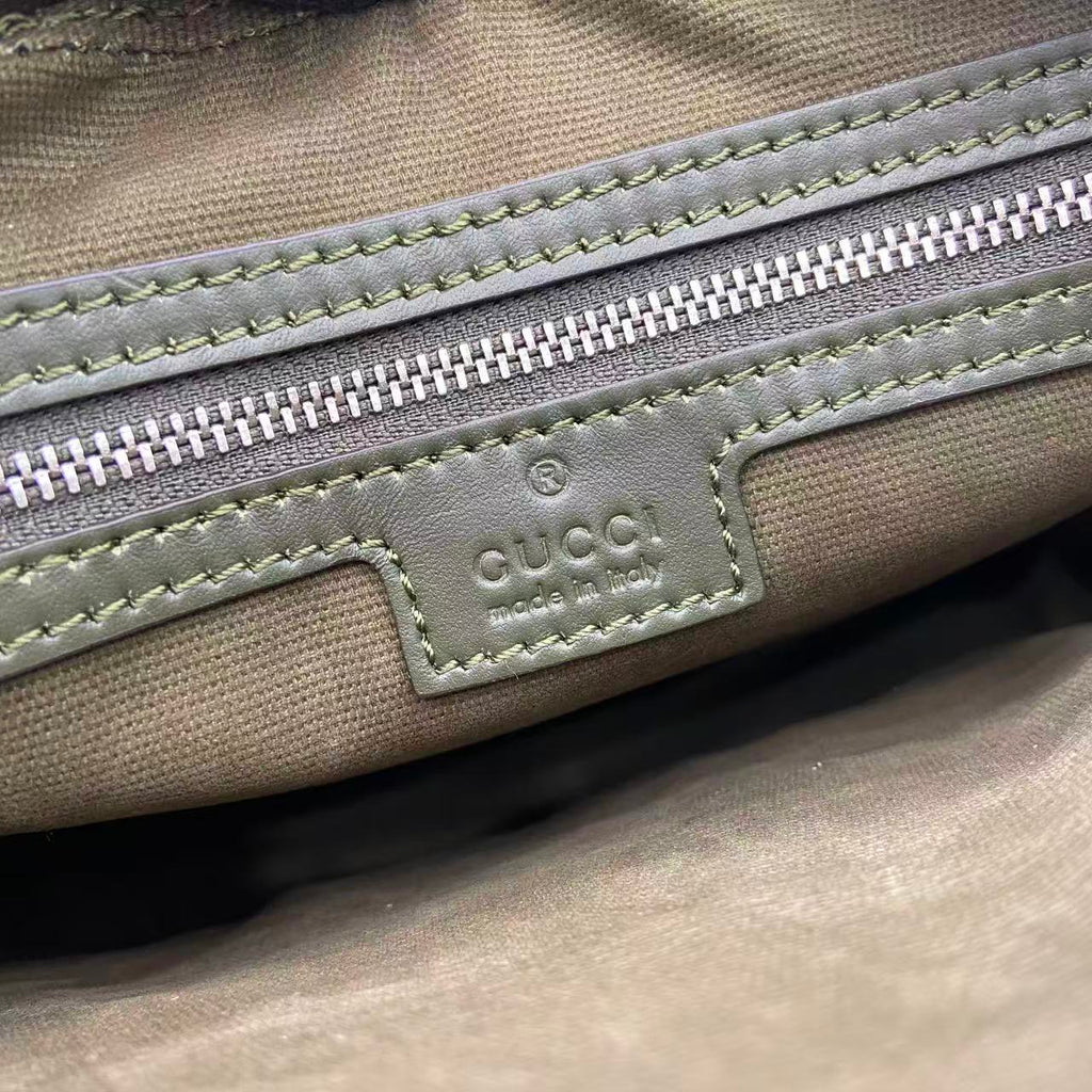 Monogram bag close-up of front logo patch, zipper, and contrast stitching