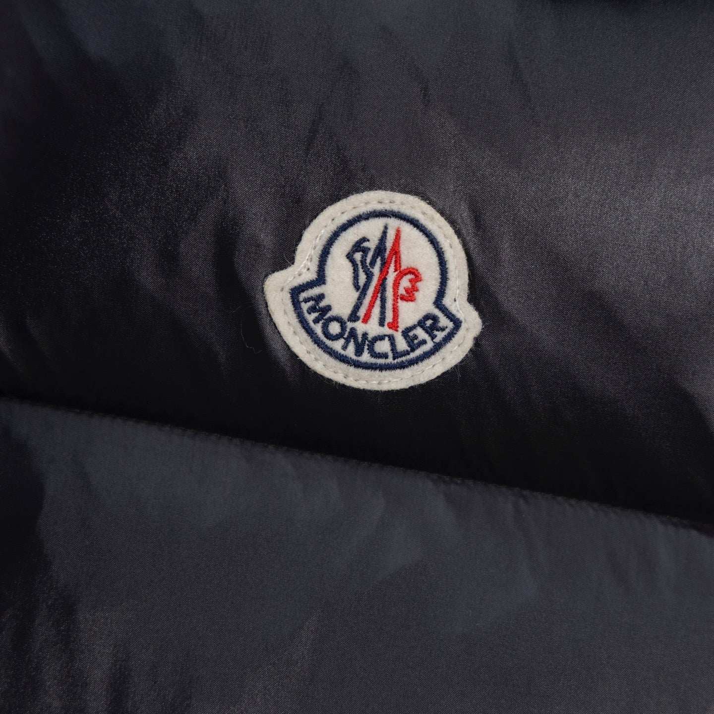 Black quilted fabric with round Moncler logo patch