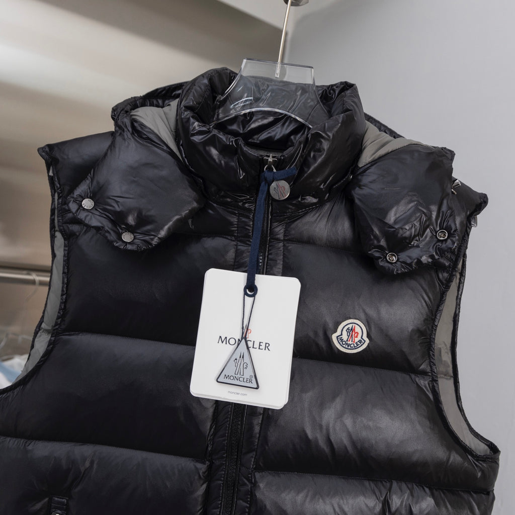 Black quilted puffer vest with hood, front zipper, and logo patch