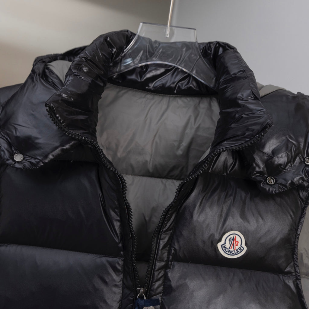 Black quilted long puffer vest with hood, front zipper, and chest logo
