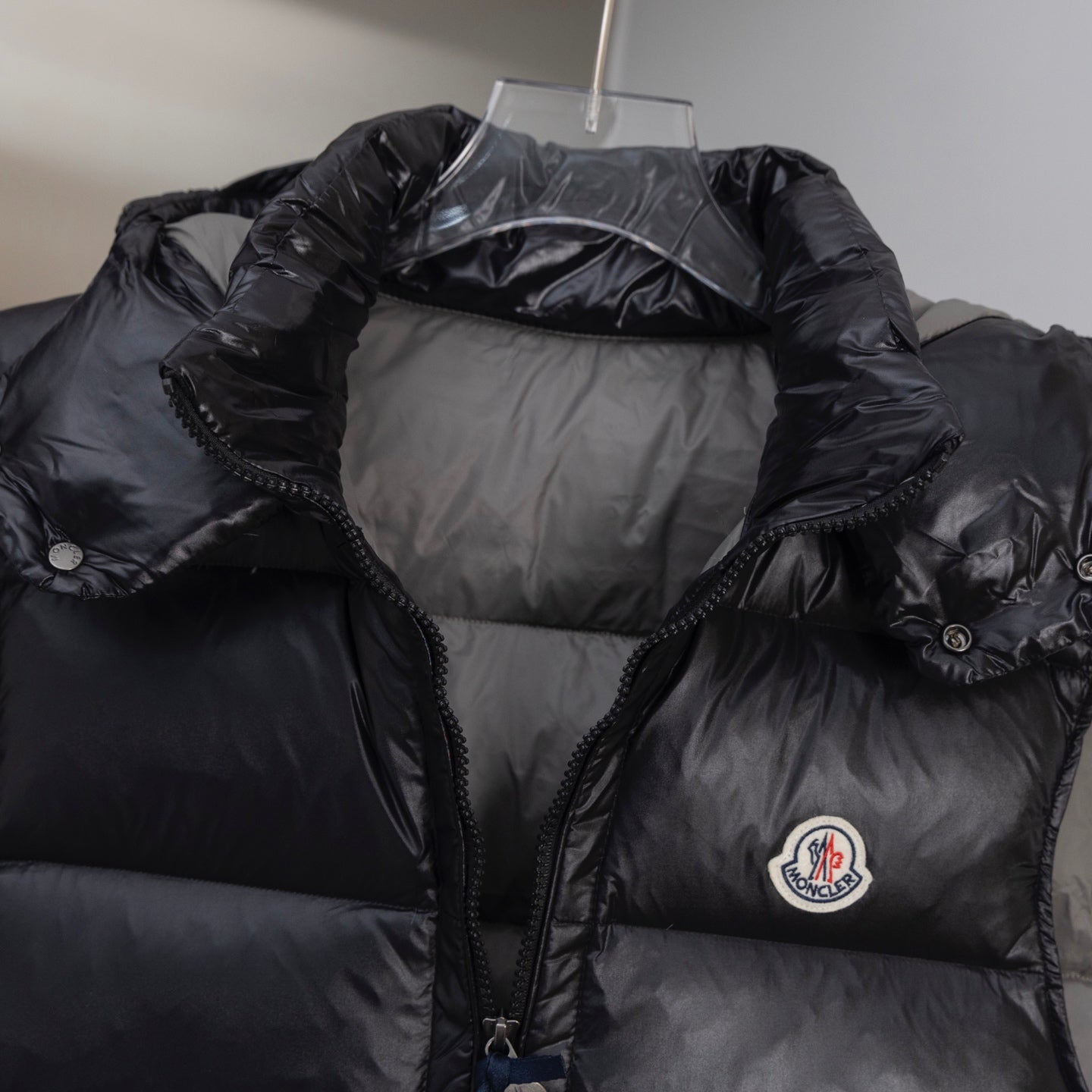 Black quilted long puffer vest with hood, front zipper, and chest logo