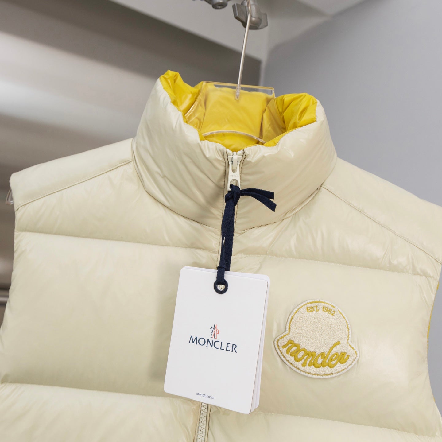 Cream padded vest with stand collar, zip front, hanging tag and logo patch