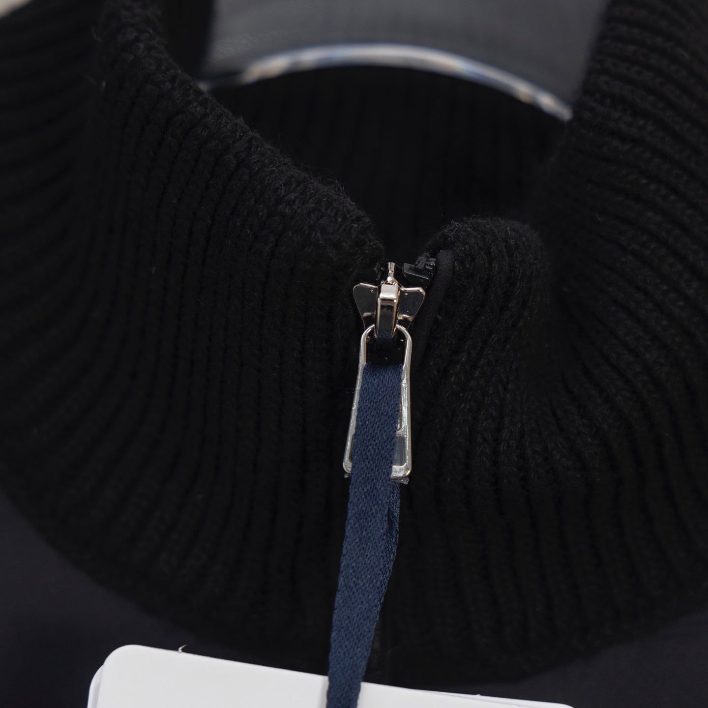 Moncler jacket zipper close-up with metal pull on ribbed knit placket