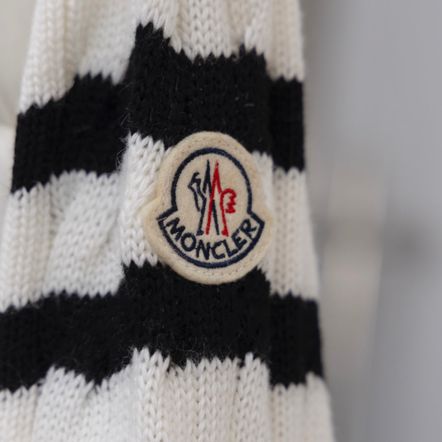 Moncler crest patch on knit sleeve, white and black striped pattern