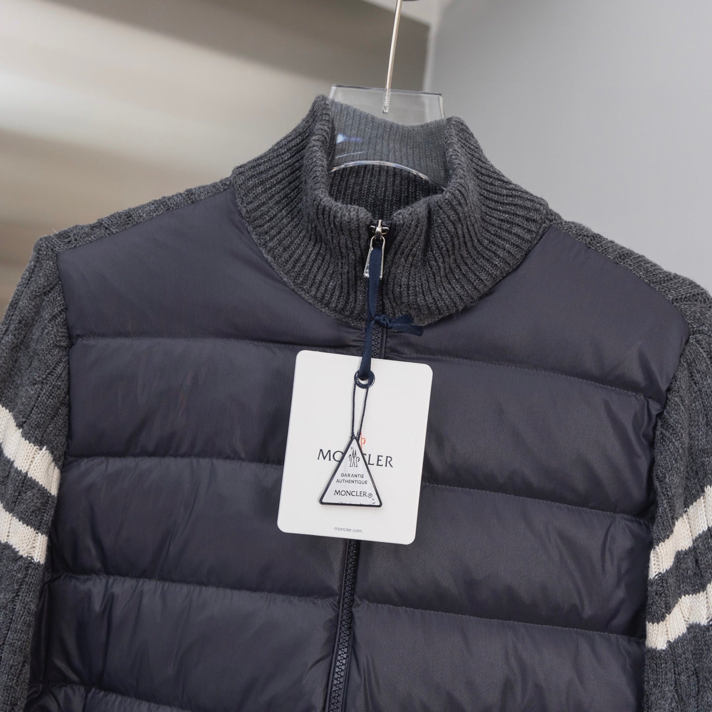 Moncler long puffer jacket with knit collar, front zip, and hanging brand tag