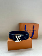 Dark navy monogram belt with gold-tone LV buckle resting on boxes