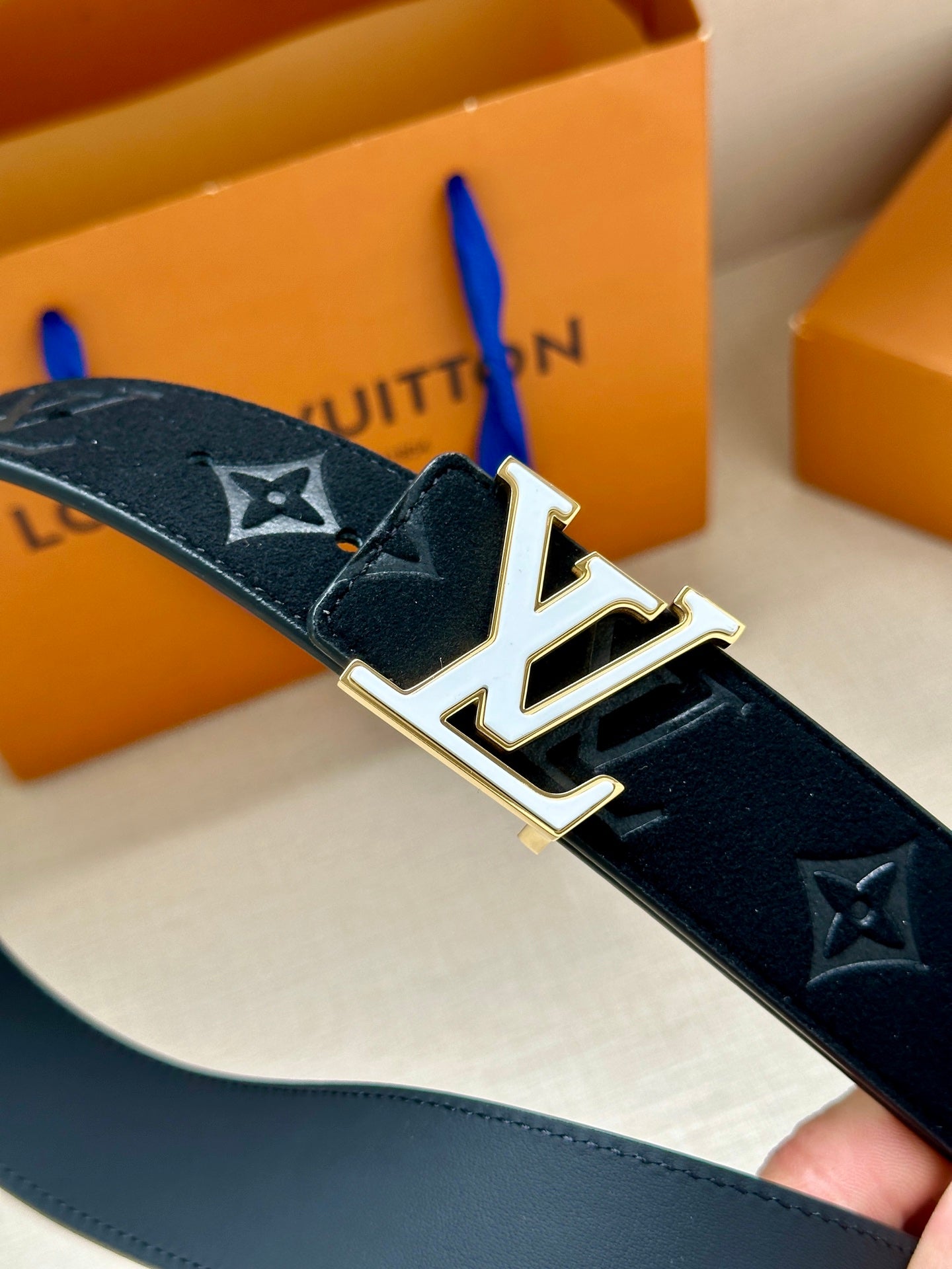 Close-up of dark navy belt with LV monogram buckle and gold-tone hardware