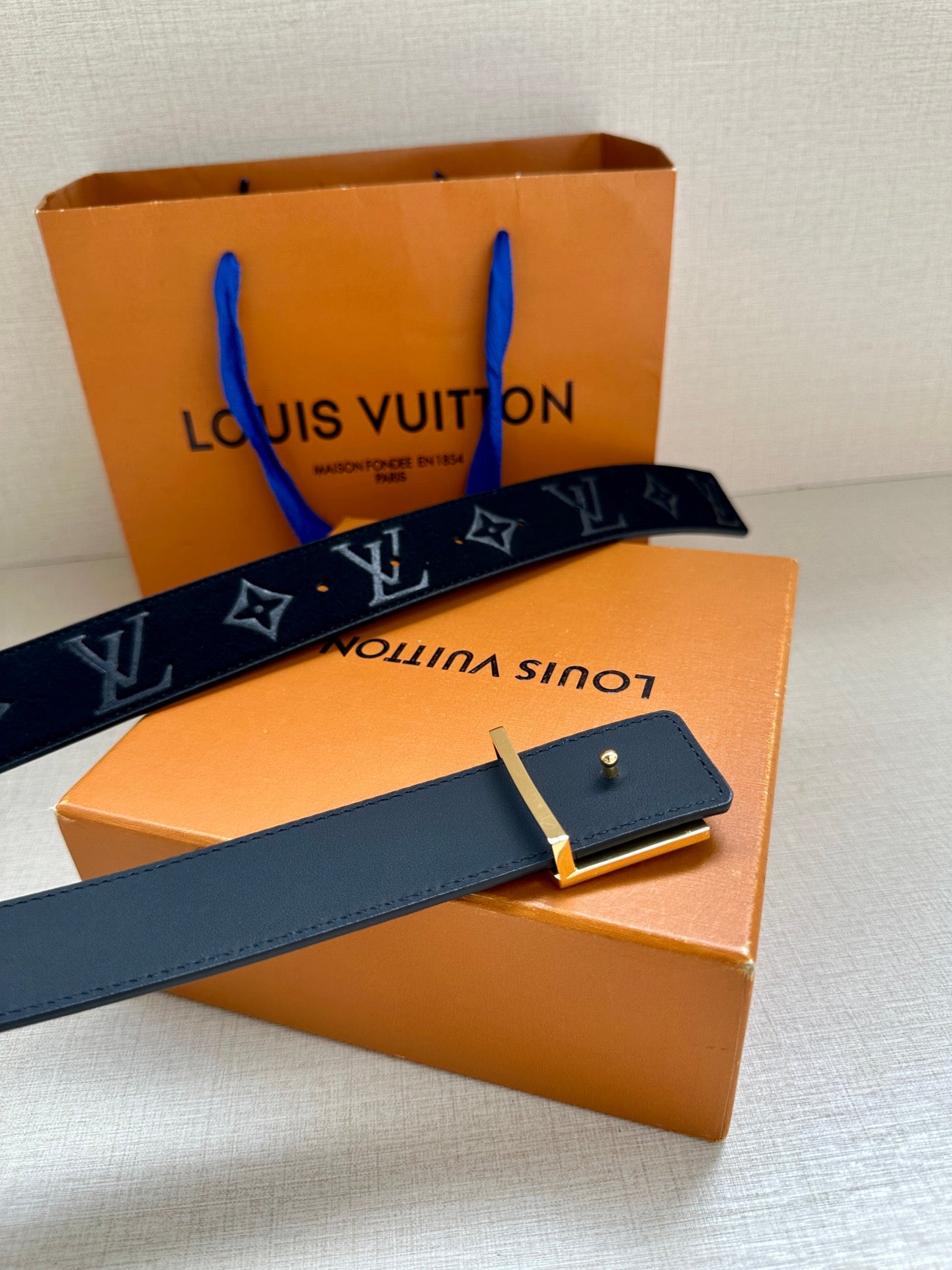 Dark navy monogram belt with gold-tone buckle and matching keeper strip