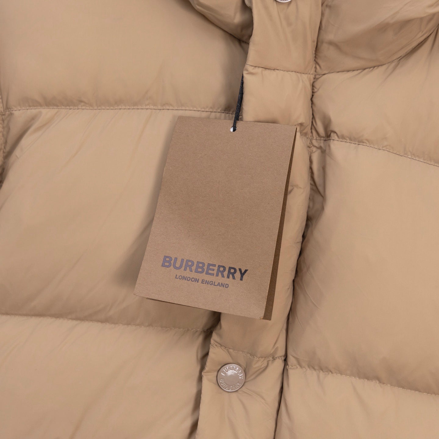 Beige puffer jacket front with Burberry hang tag and snap buttons