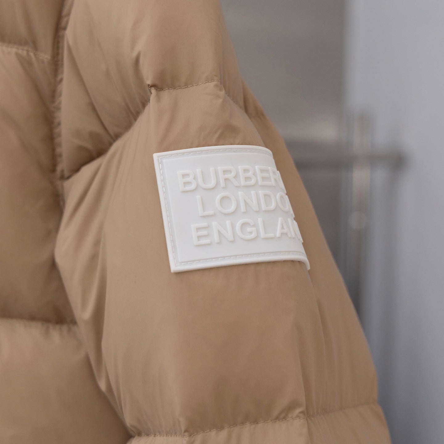 Beige puffer jacket sleeve with Burberry London England logo patch