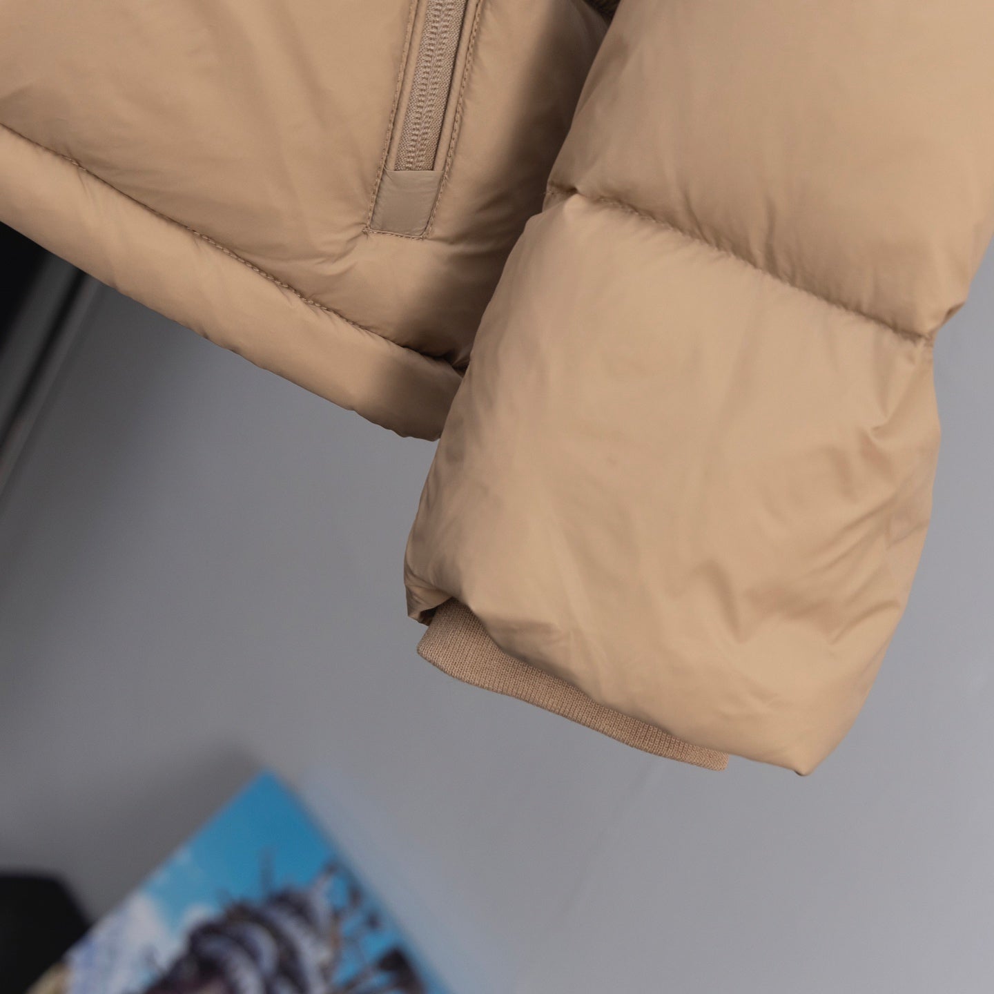 Beige puffer jacket hem with ribbed cuff and quilted panels