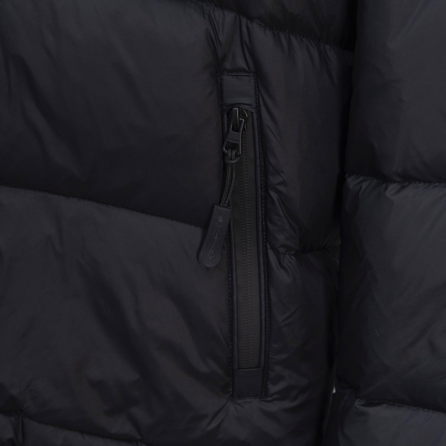 Black puffer jacket close-up of center front zipper and pocket trim