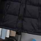 Black puffer jacket fabric close-up with horizontal quilted panels and buttons