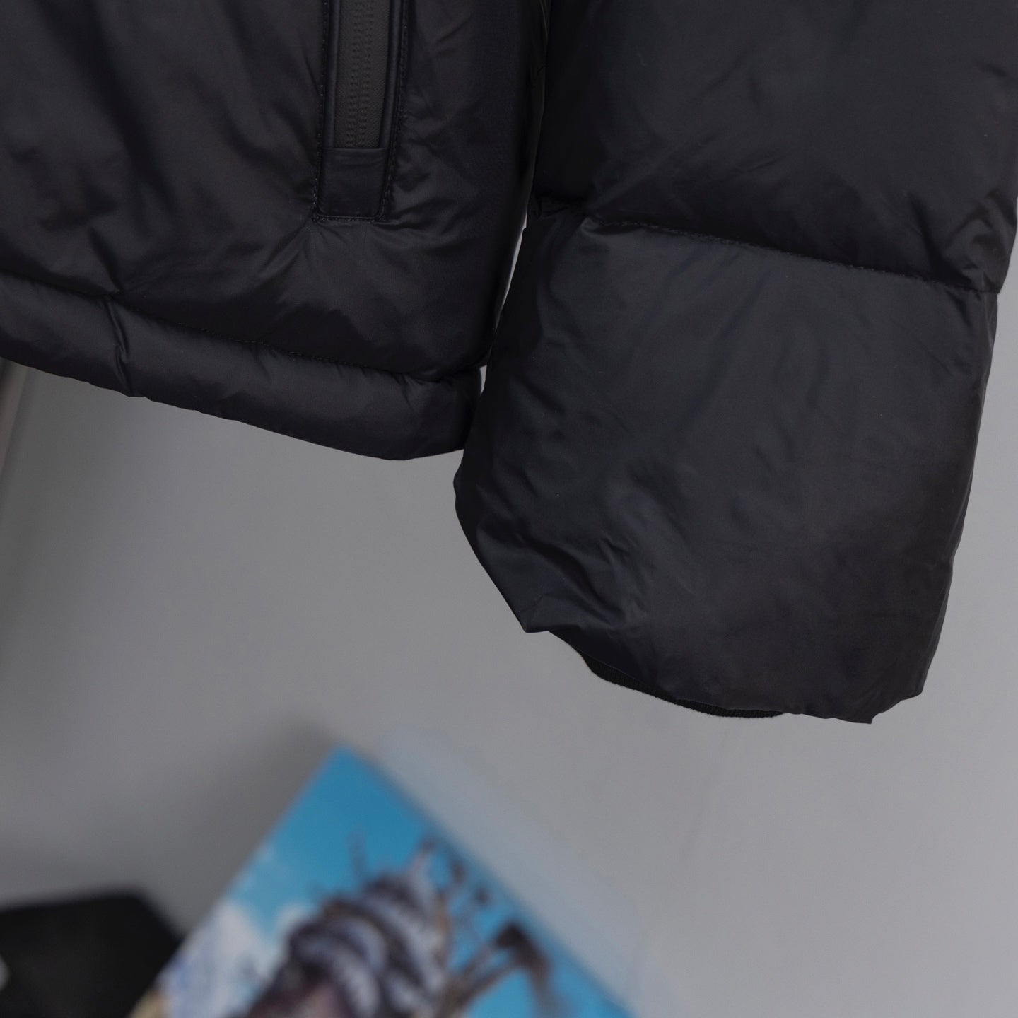 Black puffer jacket sleeve and hem close-up with textured quilted panels