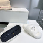 White fuzzy slide sandals with dark textured rubber outsole and logo
