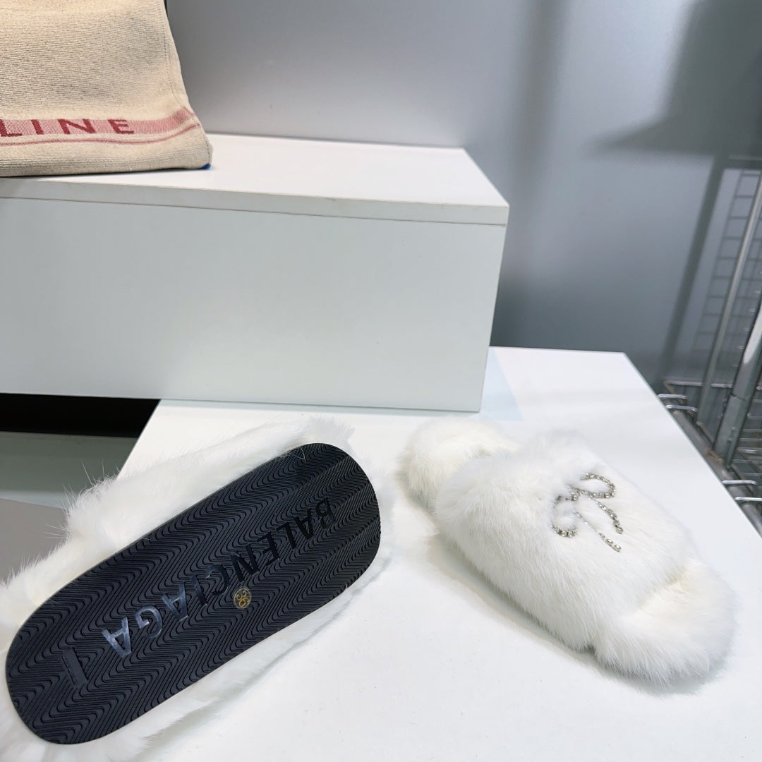 White fuzzy slide sandals with dark textured rubber outsole and logo