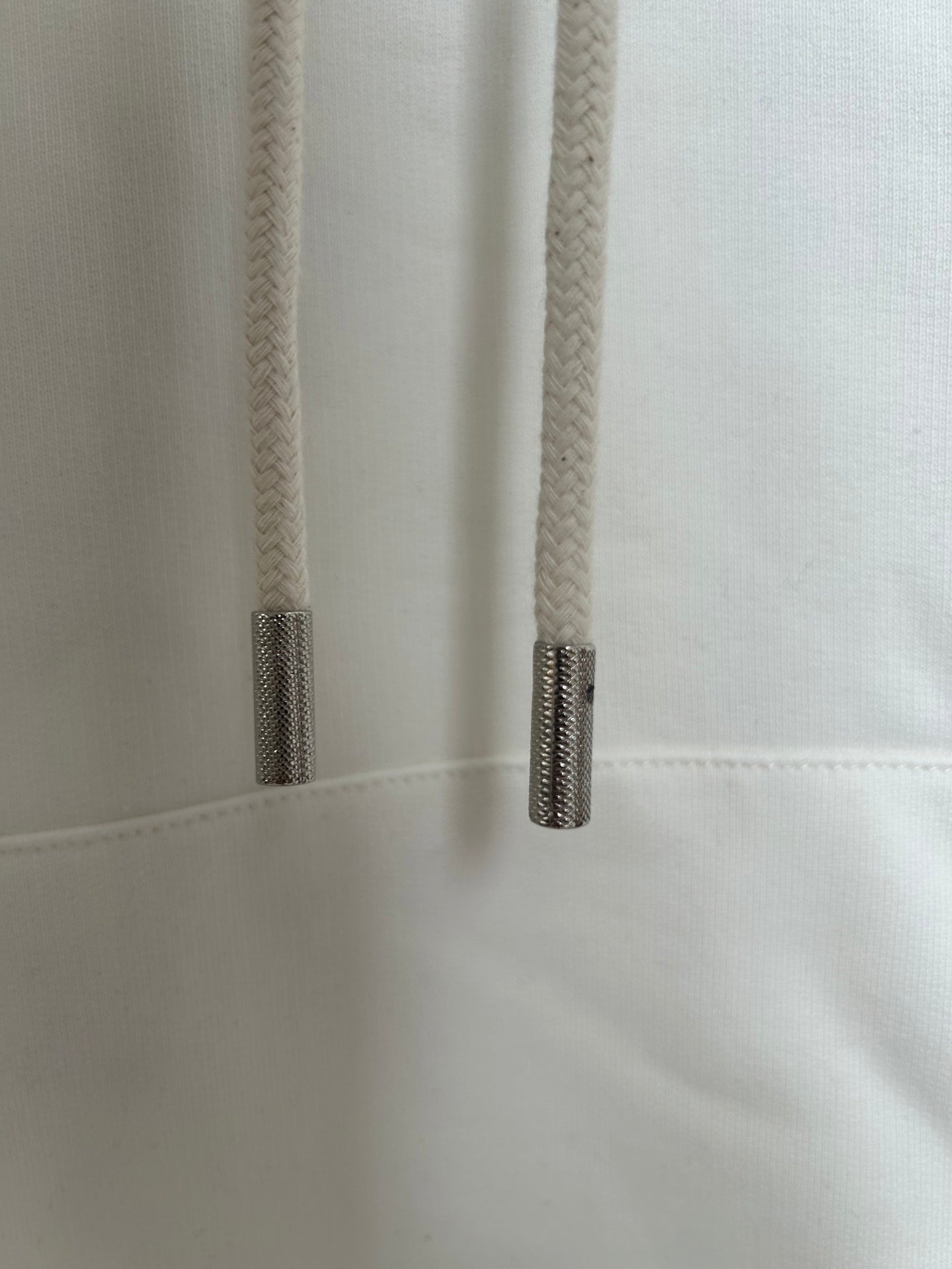 Off-white hoodie close-up of drawstring tips and stitched seam near pocket