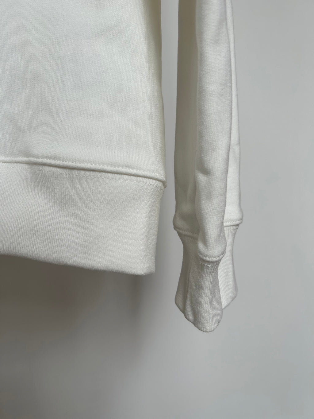 Off-white hoodie cuff and side hem close-up with smooth fabric texture