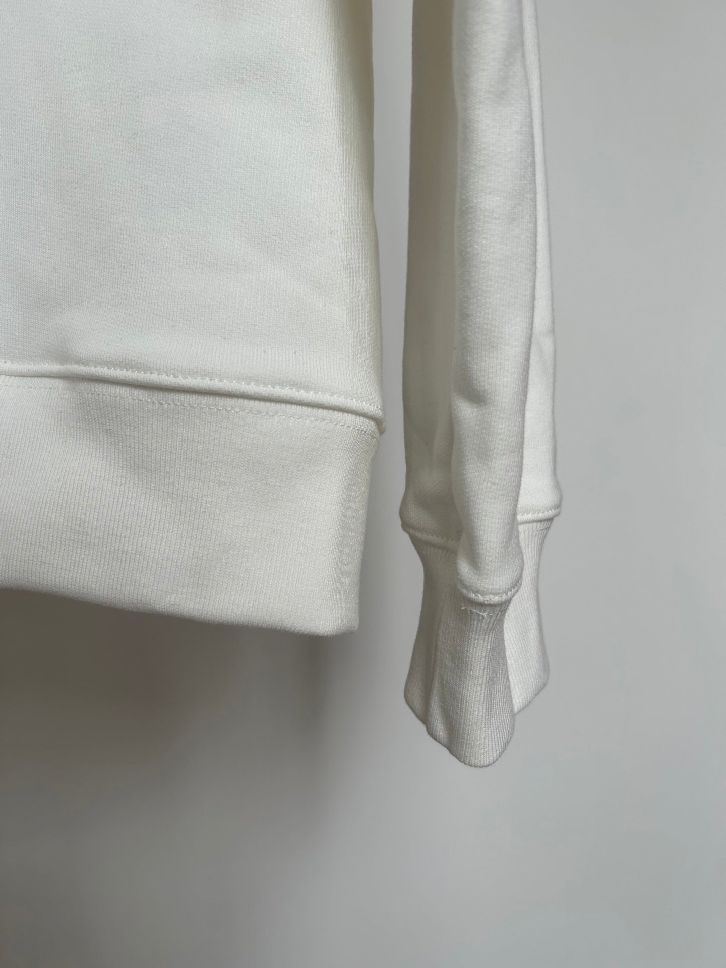 Off-white hoodie cuff and side hem close-up with smooth fabric texture