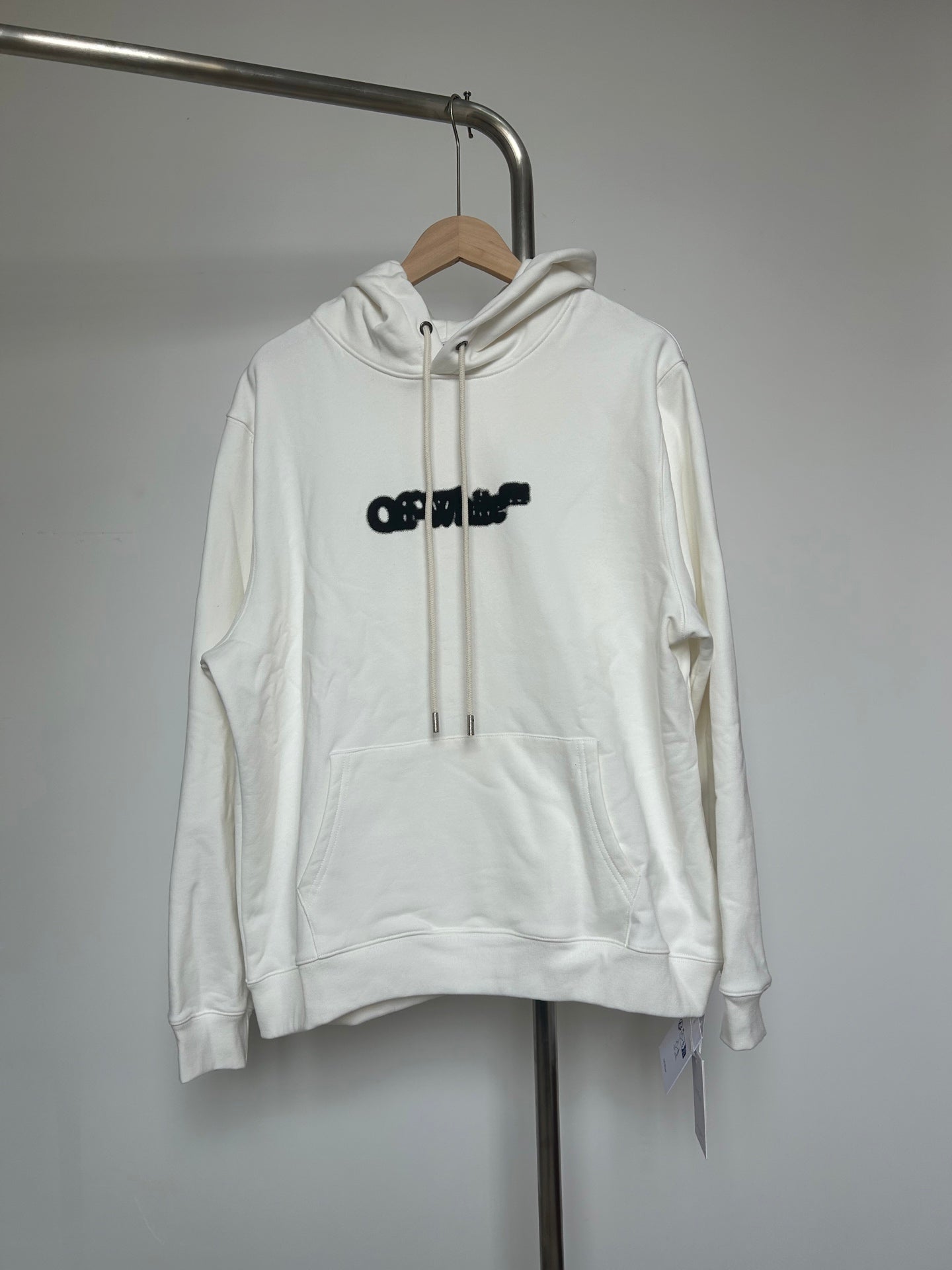 Off-white pullover hoodie with front pocket and black logo print, drawstring hood
