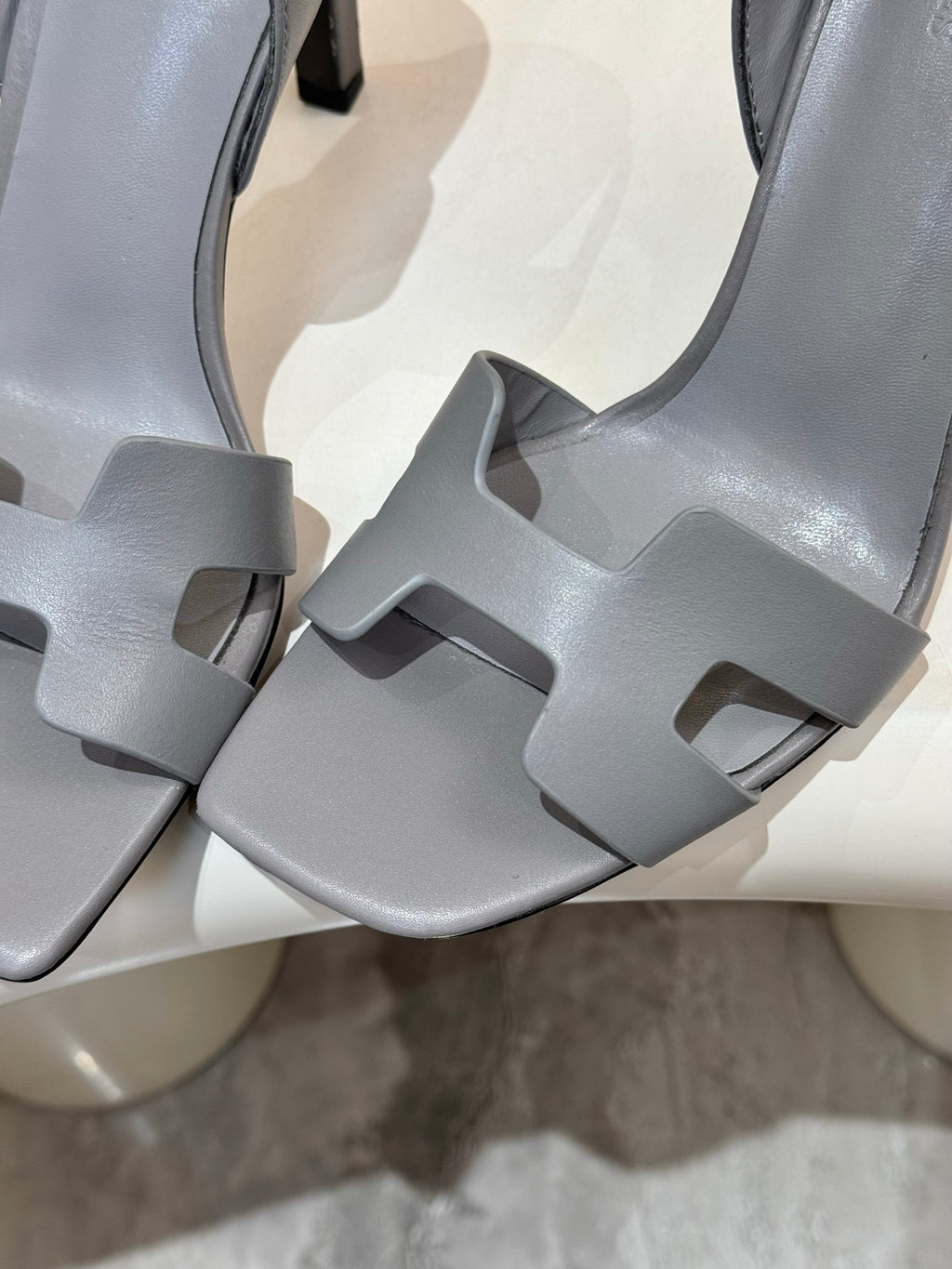 Close-up of light blue-gray heeled sandals with wide cross straps and cutouts