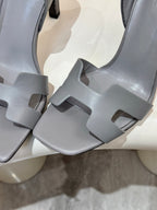 Close-up of light blue-gray heeled sandals with wide cross straps and cutouts
