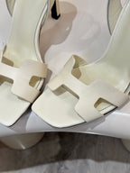 White leather heeled sandal angled close-up, T-strap with cutout design