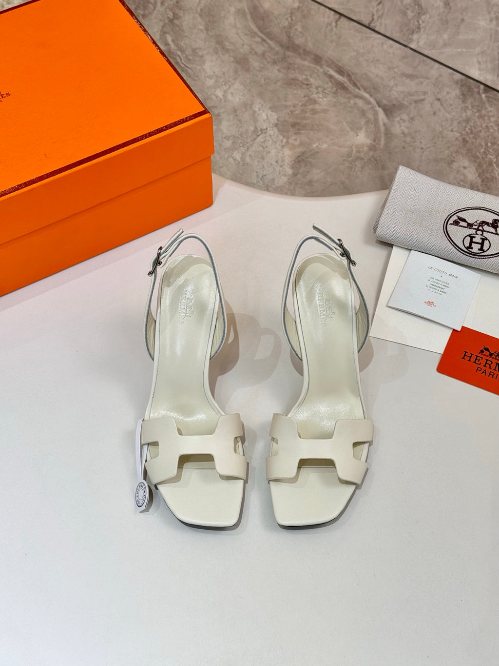 Pair of white heeled sandals with ankle straps and stiletto heels