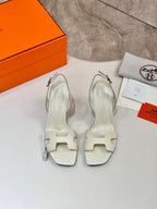 Pair of white heeled sandals with ankle straps and stiletto heels