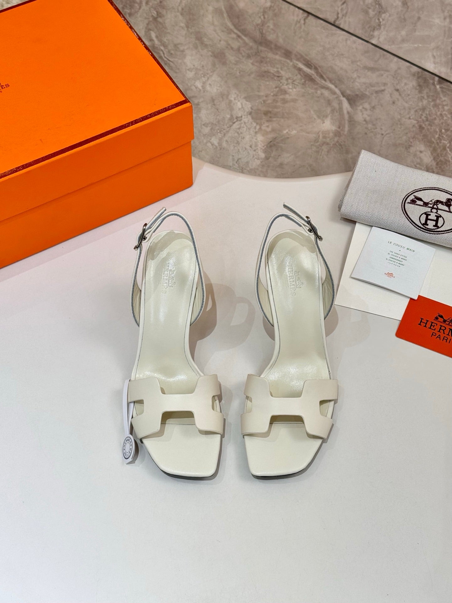 Pair of white heeled sandals with ankle straps and stiletto heels
