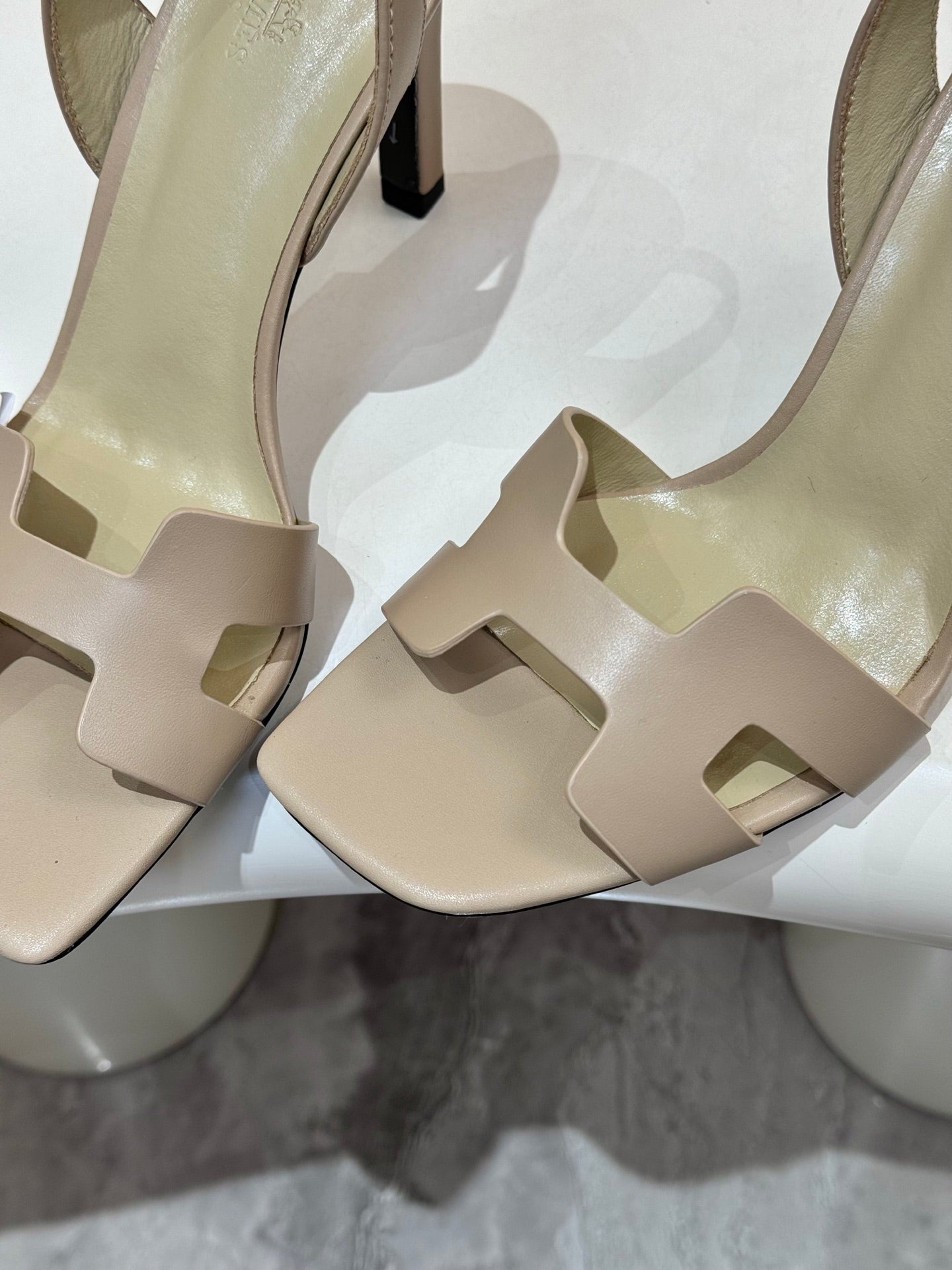 Hermes light beige heeled sandals close-up of front straps and black heel