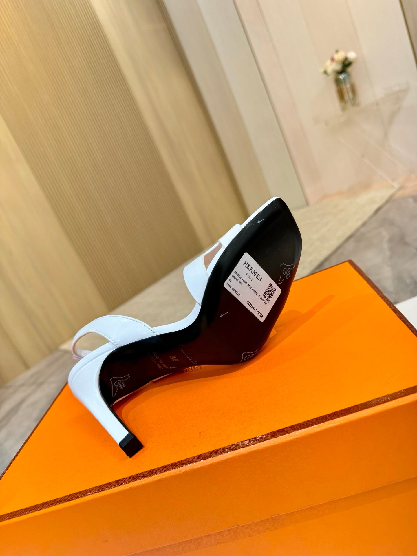 White heeled sandal shown from back with ankle strap and black heel accent