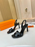 Hermes black heeled slingback sandals with wide cutout straps and sculpted heel