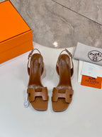 Brown leather heeled sandals laid flat, showing openwork straps and ankle strap