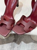 Hermes ladies' leather heeled sandals close-up: dark burgundy T-strap and buckle strap.