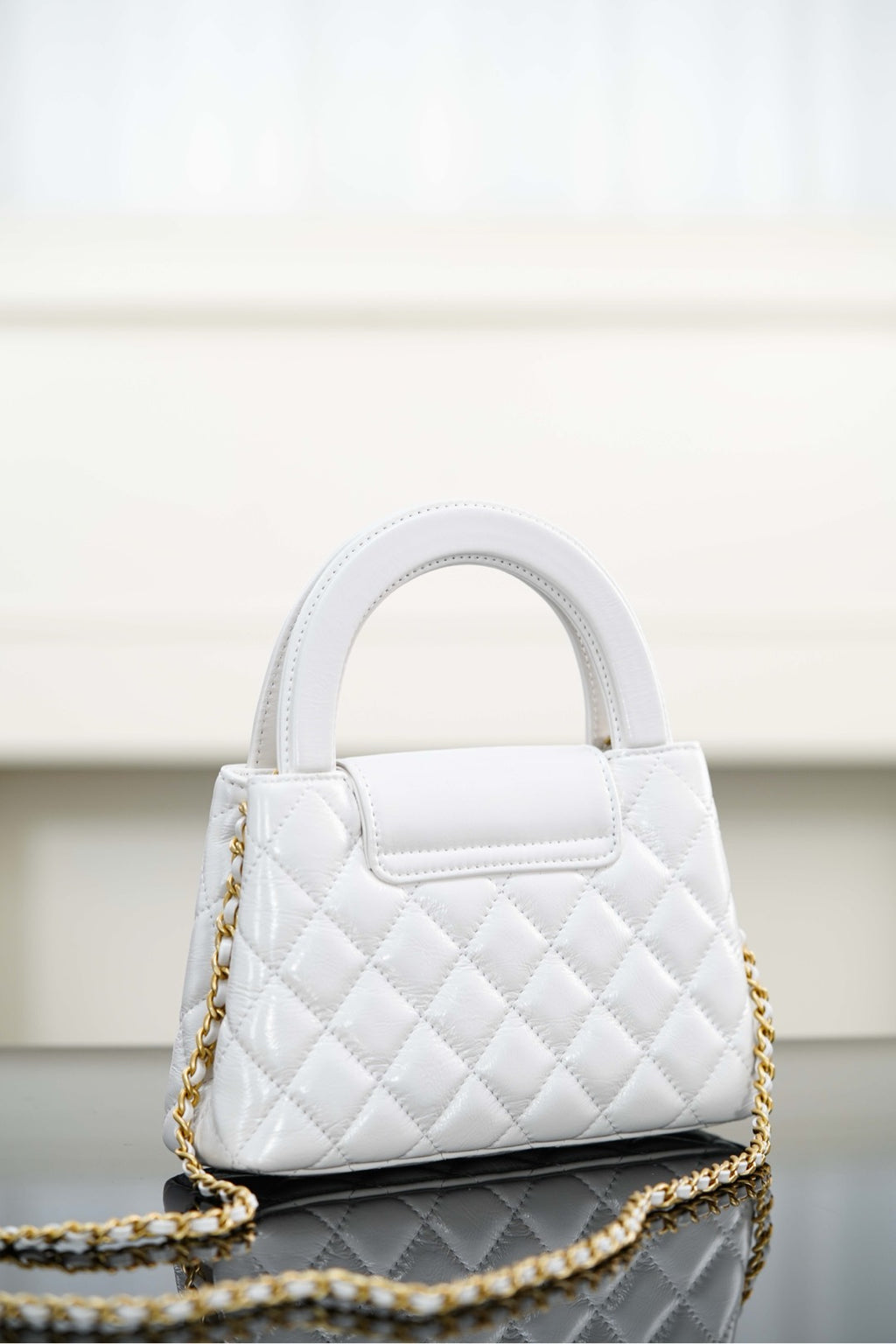 Chanel quilted handbag with top handle and gold chain strap, side view
