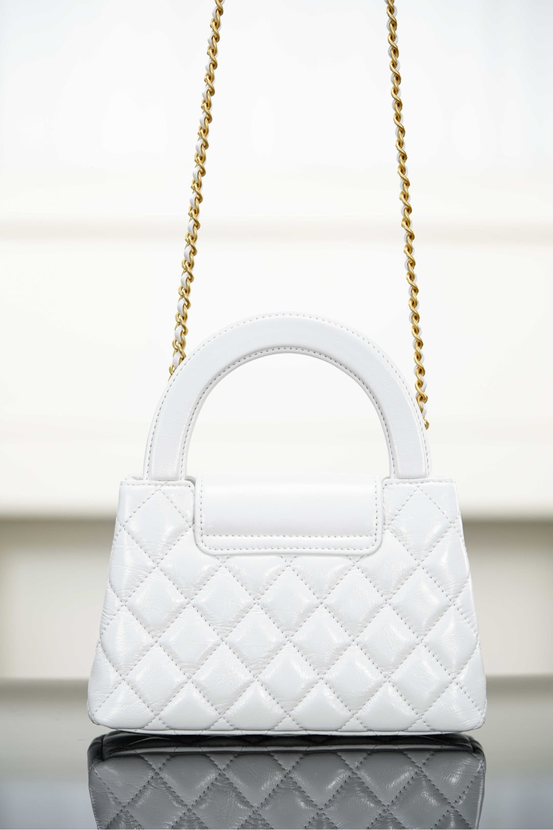 Chanel quilted handbag with top handle and gold chain strap