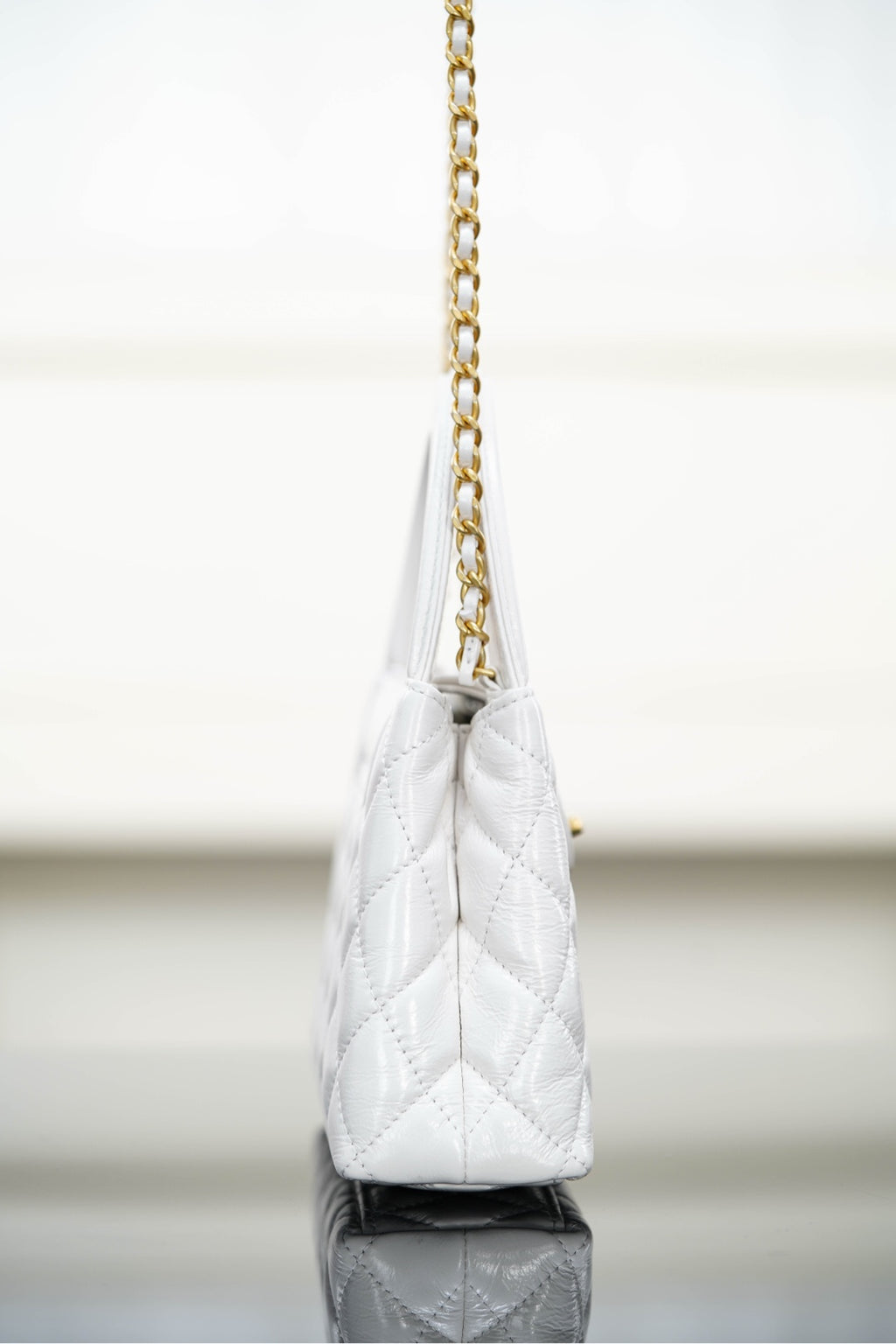 Chanel quilted handbag on a gold chain strap, angled side view
