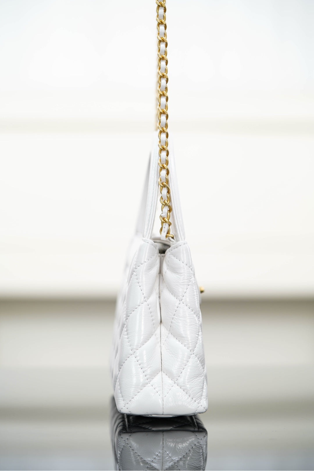 Chanel quilted handbag on a gold chain strap, angled side view