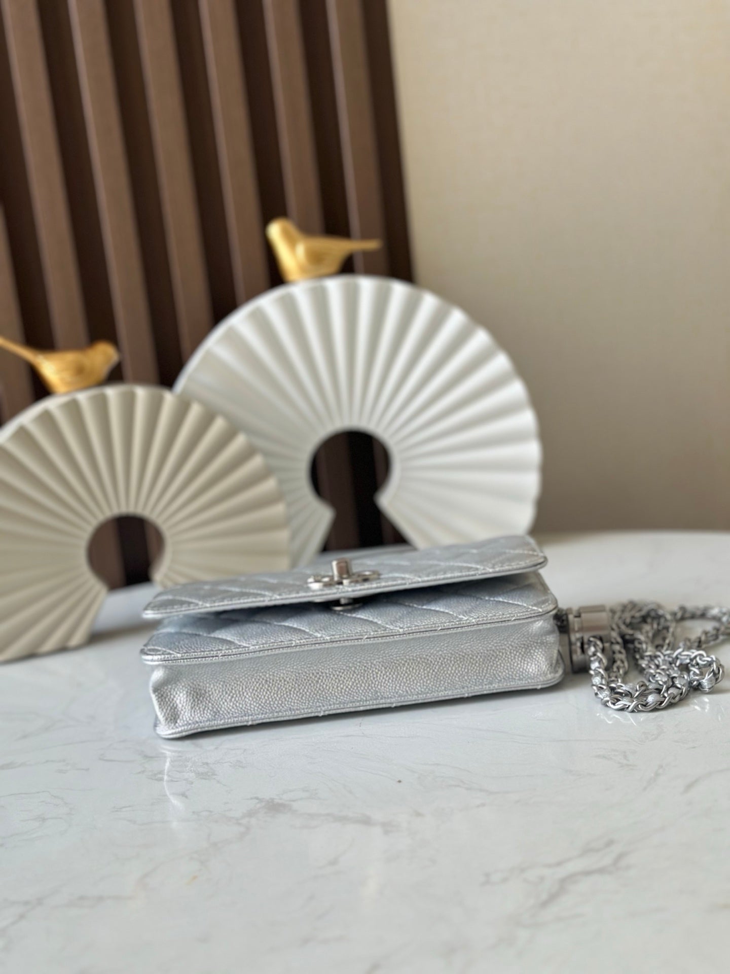 Silver Chanel mini bag with quilted texture, chain strap, and turn-lock front clasp