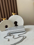 Silver quilted Chanel mini flap bag with chain strap and metal clasp, laid flat