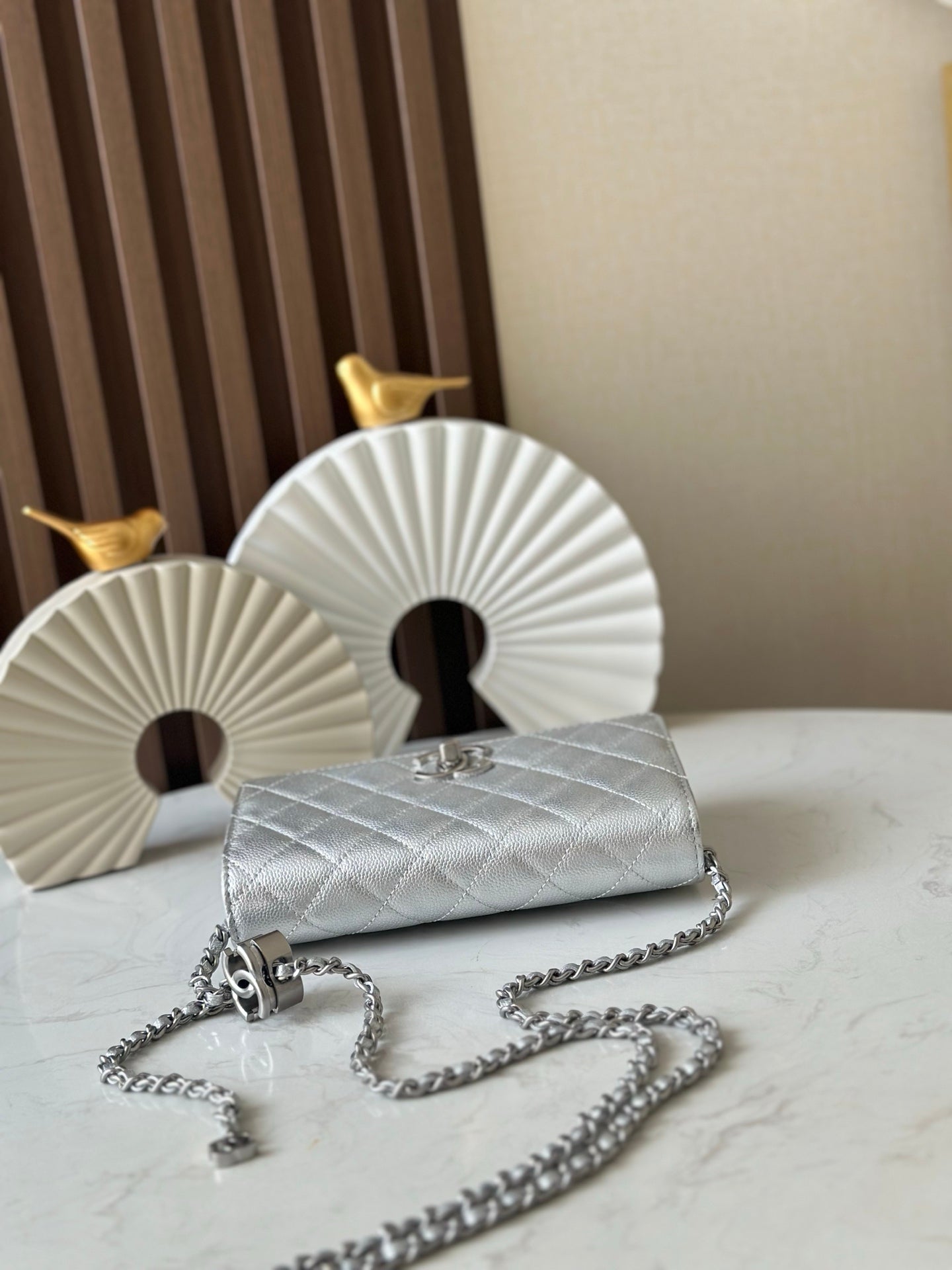 Silver quilted Chanel mini flap bag with chain strap and metal clasp, laid flat