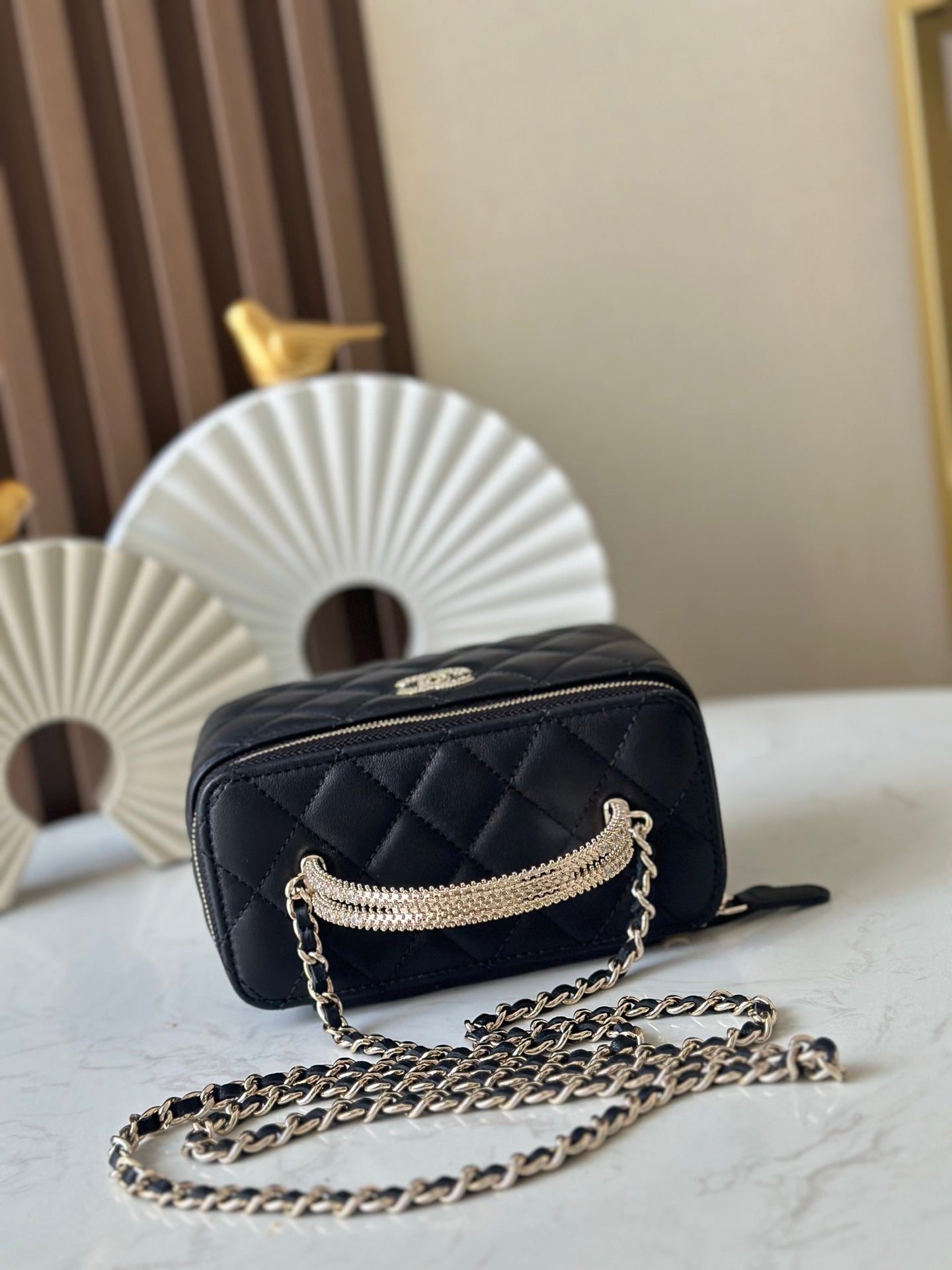Quilted black mini bag with gold zipper and chain strap, side view