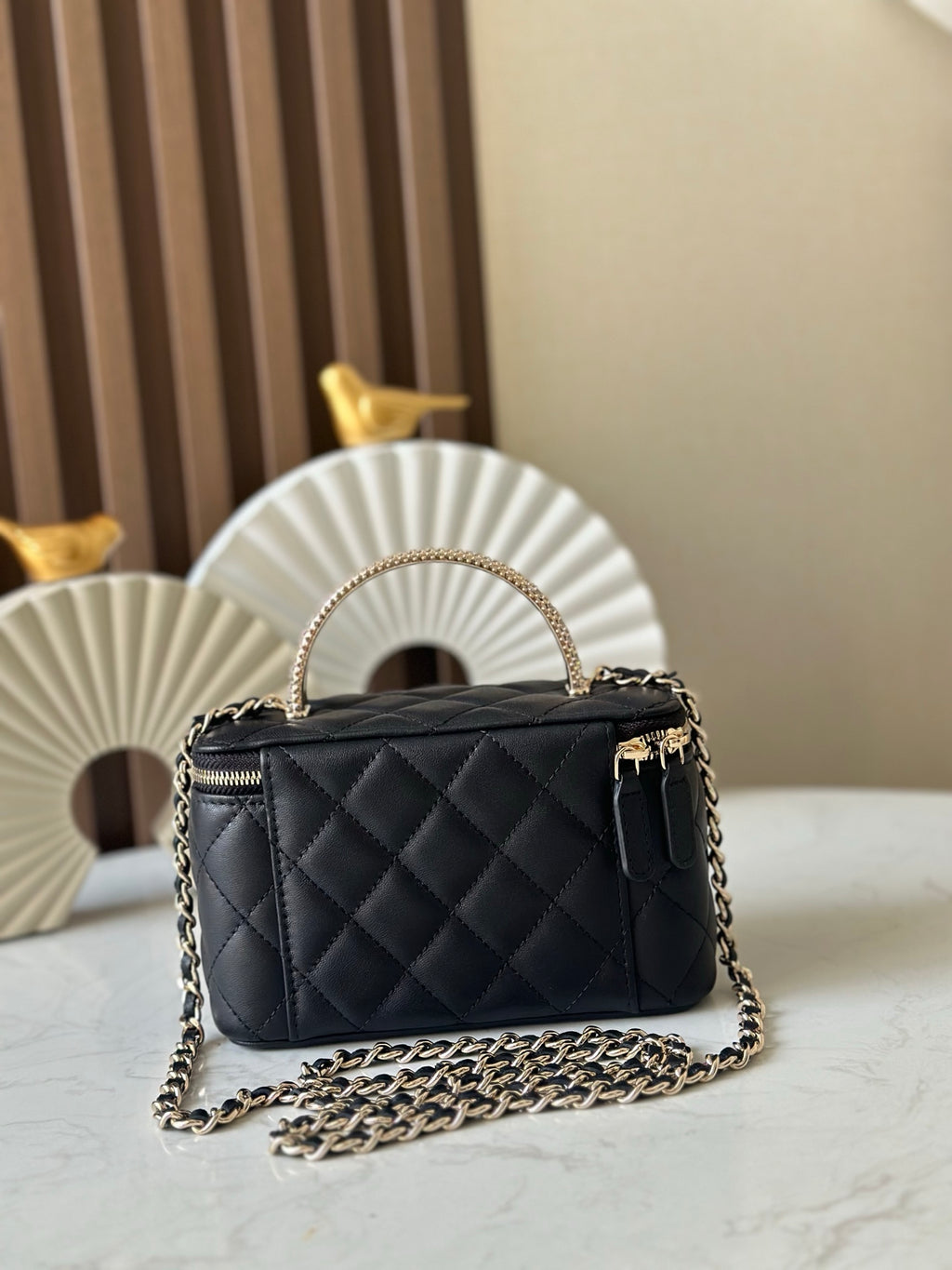 Quilted black mini handbag with top handle and gold chain crossbody strap