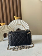 Quilted black mini handbag with top handle and gold chain crossbody strap