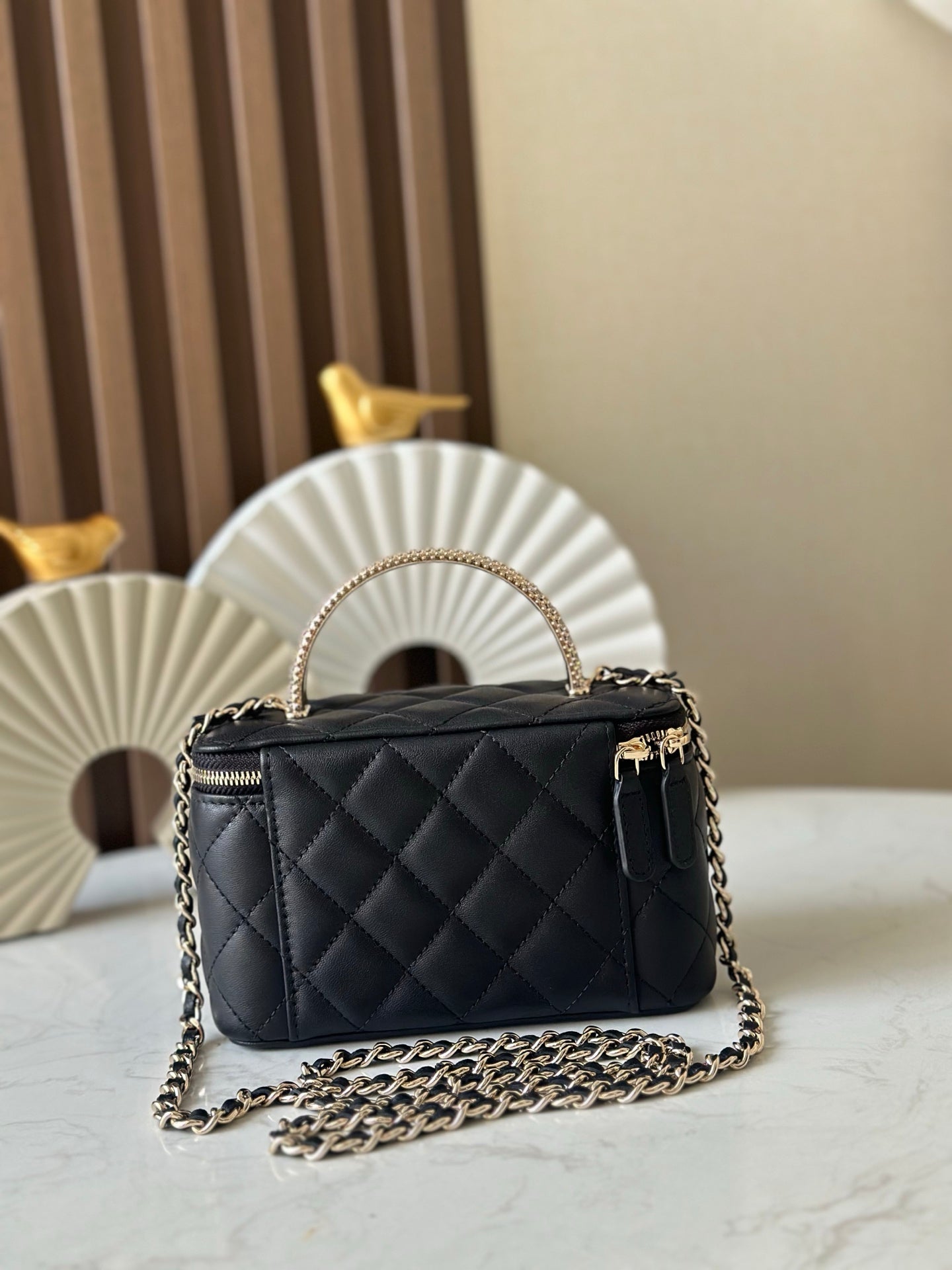 Quilted black mini handbag with top handle and gold chain crossbody strap