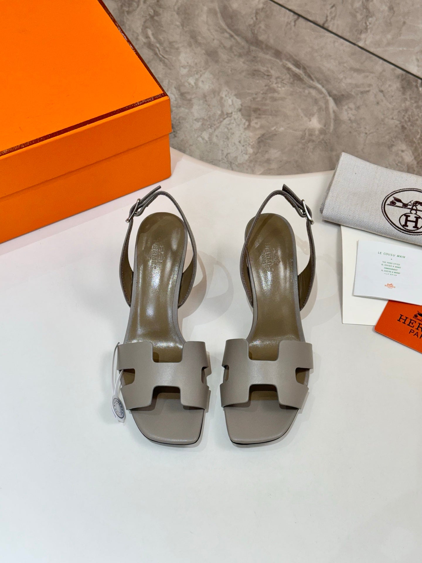 Women’s gray slide sandals with square-toe cutouts and slim heel, on display