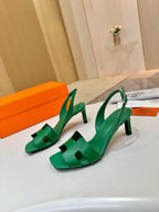 Pair of green leather heeled sandals with T-strap and slingback straps on display